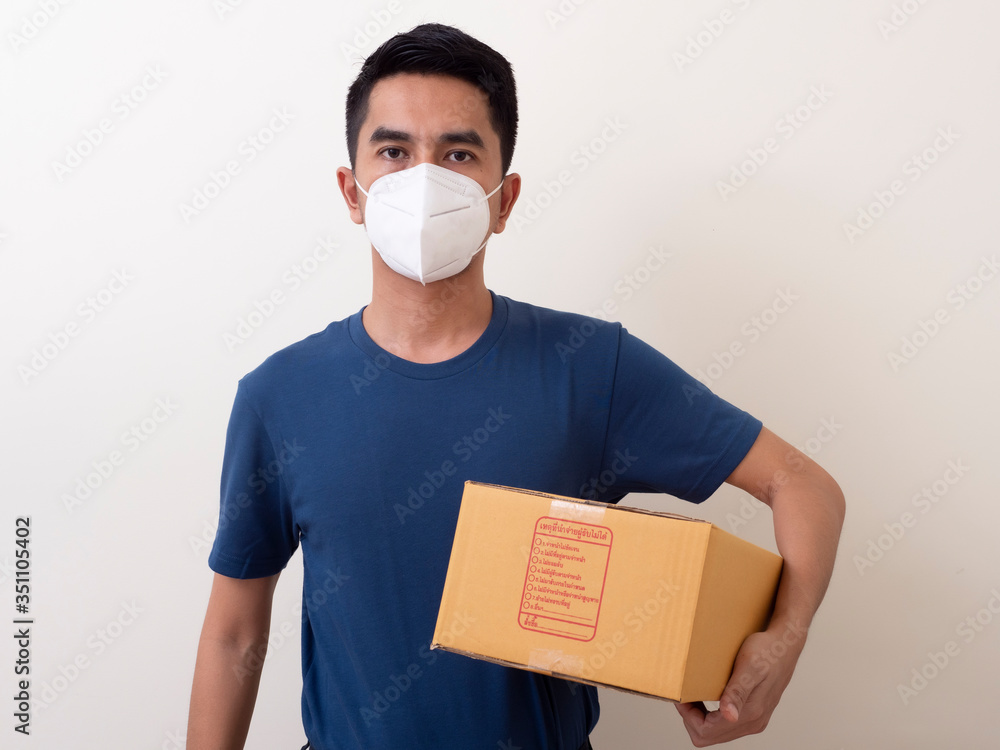 Happy delivery service employee in medical face mask carry cardboard box in hand Happy delivery service employee in medical face mask carry cardboard box in hand