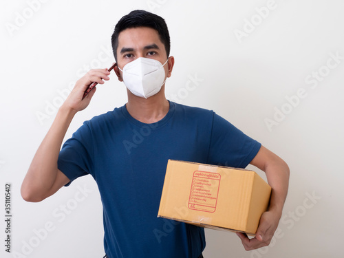 Happy delivery service employee in medical face mask carry cardboard box in hand