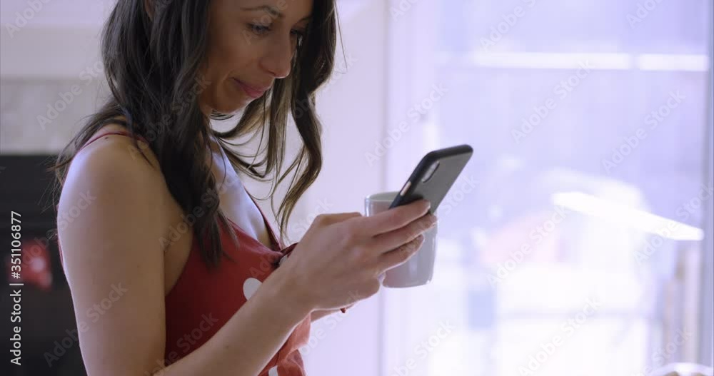 Woman receives interesting message while sipping morning coffee - close up Woman receives interesting message while sipping morning coffee - close up