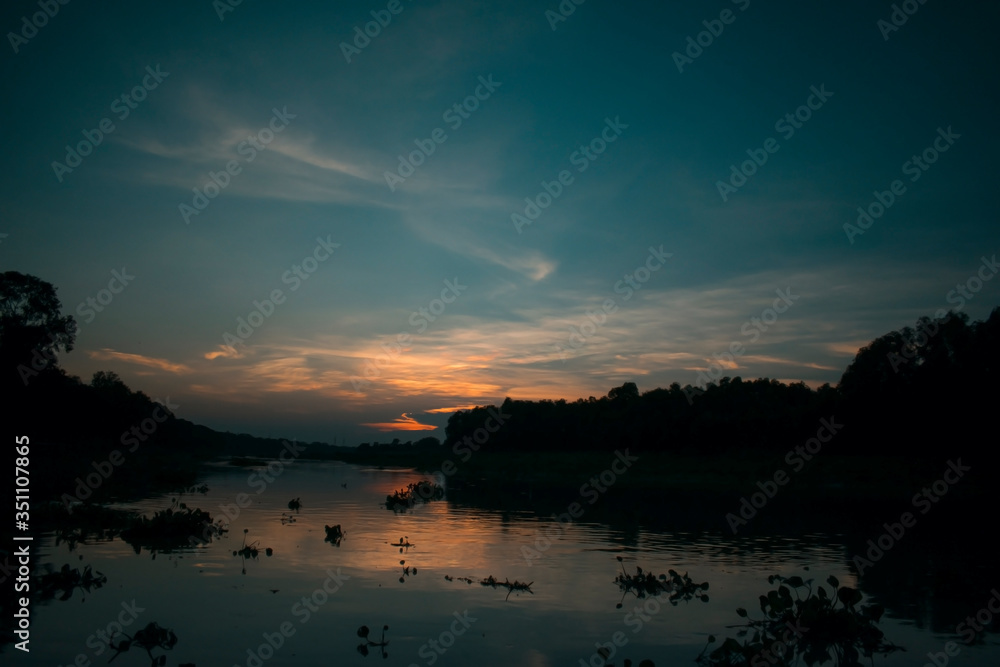 silhouette sunset landscape over a kalindri river of malda with orange and blue sky