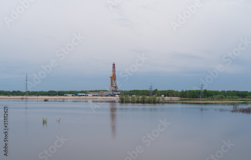 Drilling rig and work trailers on the plain by the lake on a cloudy evening. © IURII