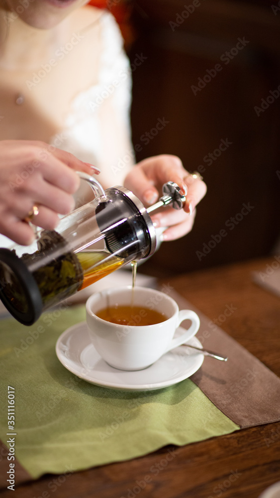 Pours herbal tea into a mug.