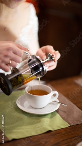Pours herbal tea into a mug.