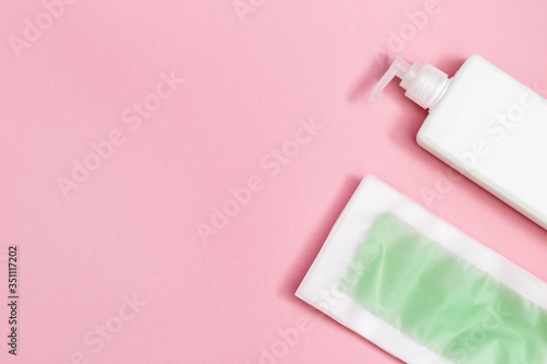 Set of female of hair removal. Wax strips, body moisturizer on pink paper background with copy space. Top view.