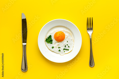 Fried eggs on plate - yellow table top view