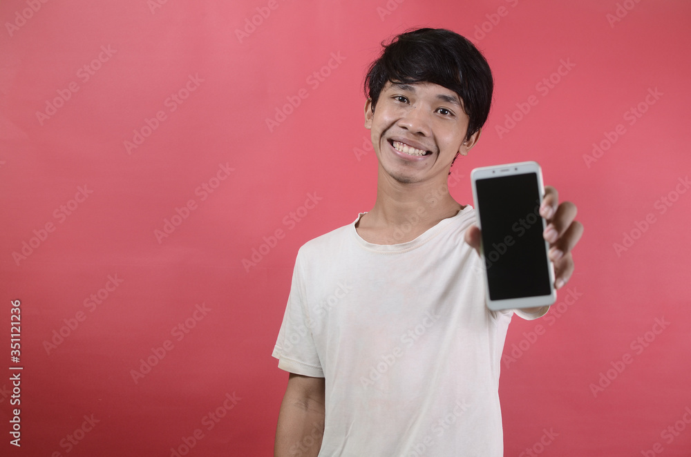 Happy smiling young Asian man showing mobile phone. Asian men wearing white t shirts isolated on a red background Happy smiling young Asian man showing mobile phone. Asian men wearing white t shirts isolated on a red background