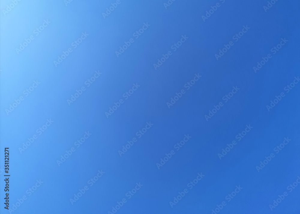 Obraz premium blue sky background with white flare on the sky. Blue color gradian background.