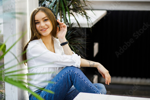 Smiling young woman at the cafe with headphones listening to music