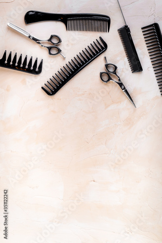 Combs, hairbrush, scissors - hairdresser eqiupment - on beige table top-down space for text