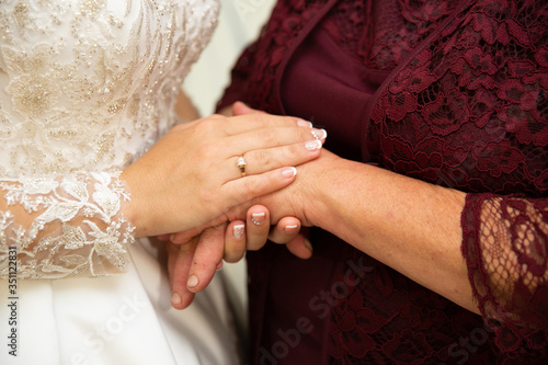Bride is brushing mom's hands on wedding day.