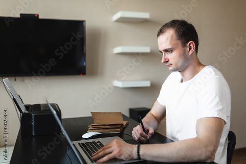 Male freelancer businessman working with a graphics tablet in an image editor. Work at home during an epidemic. Self-isolation.
