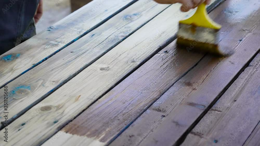 Decorating the old board with brown impregnation. Paint on wood, for protection. Home construction. Decorating the old board with brown impregnation. Paint on wood, for protection. Home construction.