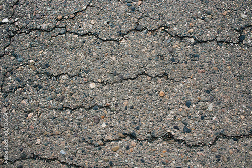 Old worn and cracked asphalt with cracks. Cracked asphalt background. Gray asphalt background