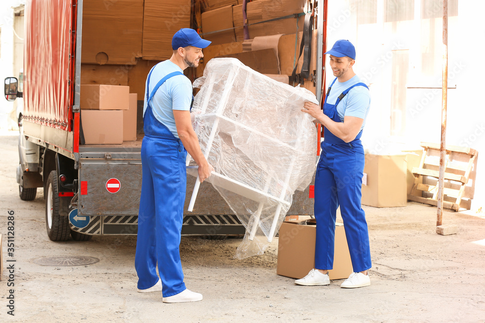 Fototapeta premium Loaders taking furniture from truck outdoors