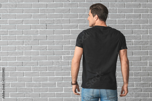 Man in stylish t-shirt on brick background