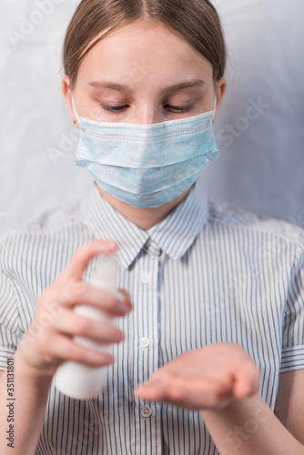 teenager girl in medical mask, antiseptic spray bottle, hand from bacteria, prevention of virus infection safety, carefully flu disease, stay home, stop pandemic of coronovirus covid 19