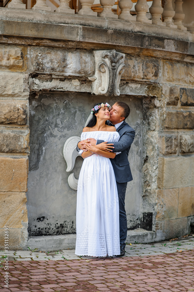 Wedding photo session on the background of the old building. The bride and groom gently hug each other. Wedding photo session on the background of the old building. The bride and groom gently hug each other.