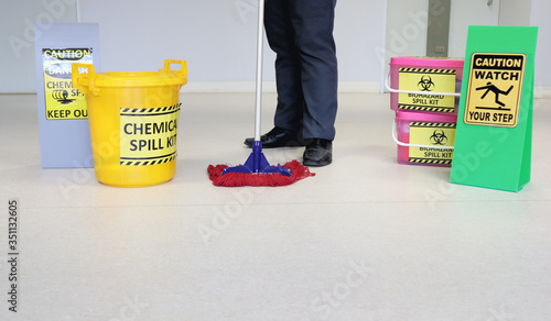 Janitor male cleaning floor in medical service room or laboratory with caution tag sign watch your step and Biohazard spill kit, chemical spill kit yellow bucket for response chemical spill out cases.