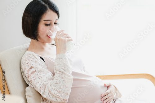 Asian pregnant woman drinking a glass of milk. Mom and kids, mother healthy and newborn preparation concept.