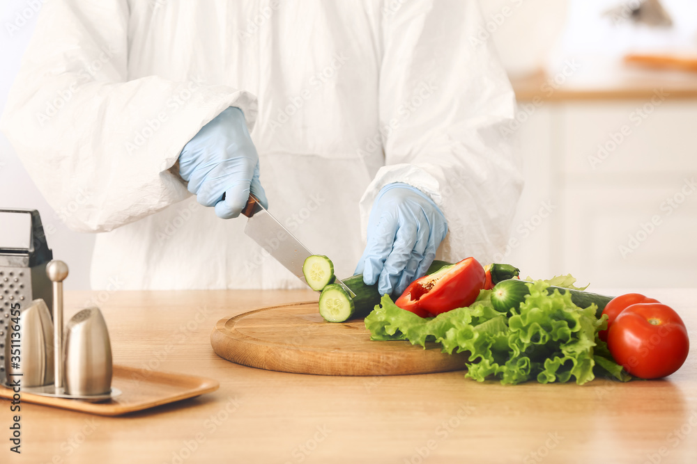 Woman in biohazard suit cooking in kitchen Woman in biohazard suit cooking in kitchen