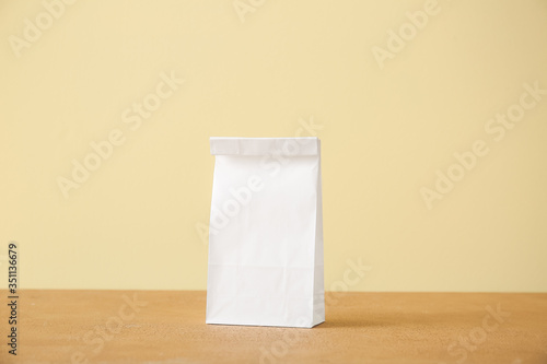 Paper bag on table against color background