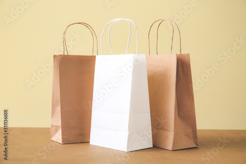 Paper bags on table against color background
