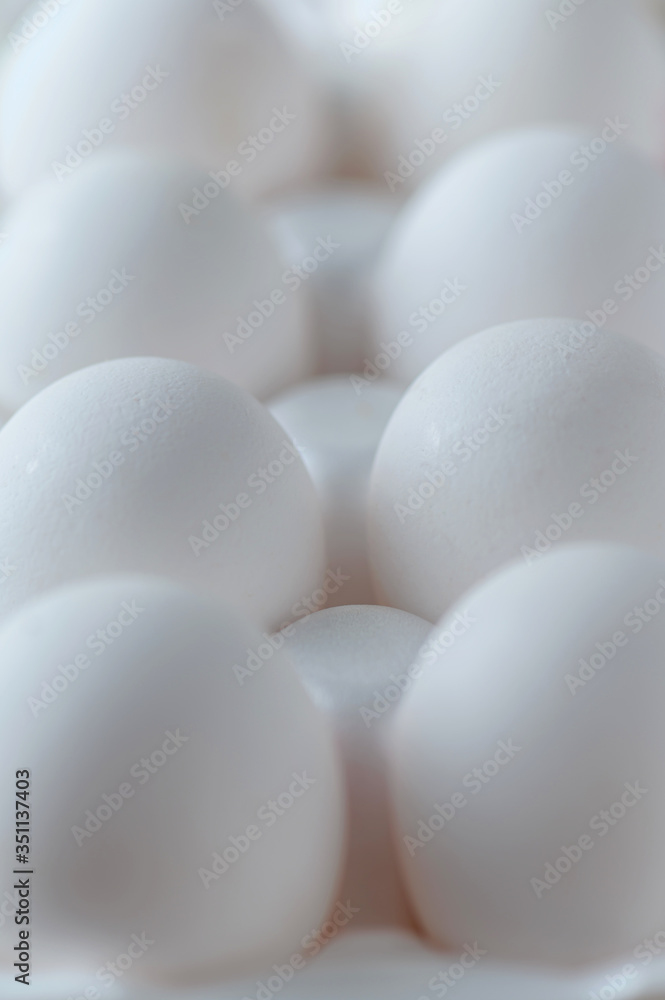 White raw chicken eggs in a plastic tray close-up. Chicken eggs background.