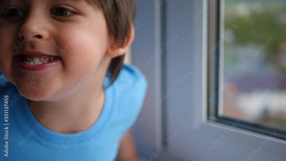 happy child in a blue t-shirt and tights sitting on a windowsill on a high floor in spring happy child in a blue t-shirt and tights sitting on a windowsill on a high floor in spring