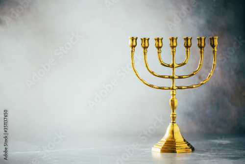 Golden hanukkah menorah on grey background. Jewish holiday banner with copy space. Ancient ritual religious candle menorah photo