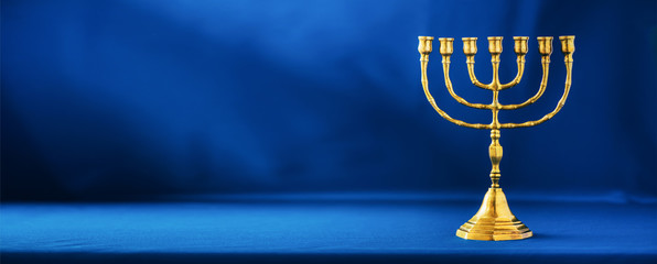 Golden hanukkah menorah on blue background. Jewish holiday banner with copy space. Ancient ritual religious candle menorah