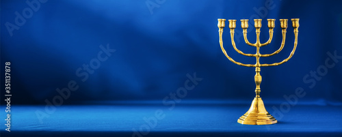 Golden hanukkah menorah on blue background. Jewish holiday banner with copy space. Ancient ritual religious candle menorah photo