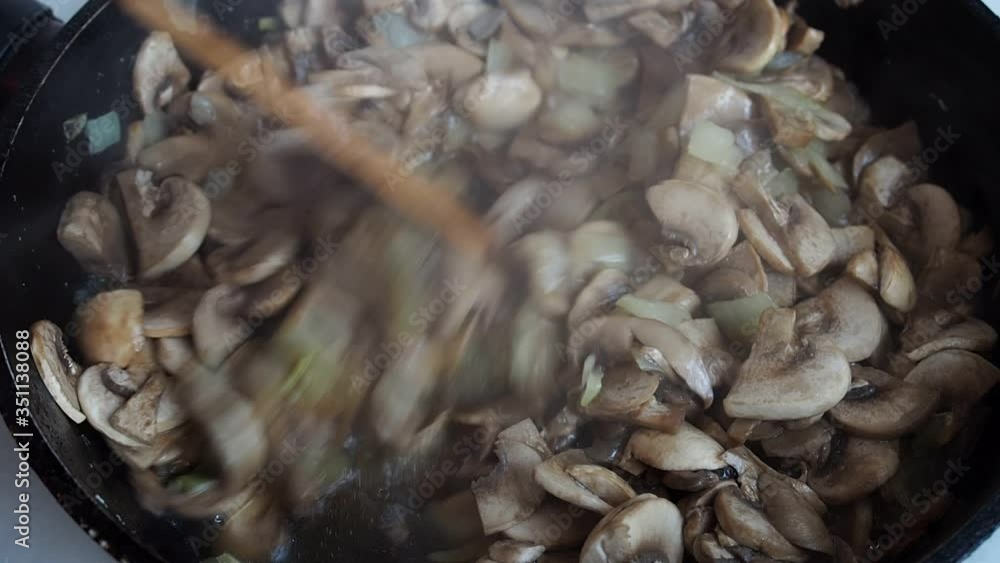 Onions and mushrooms champignons fried in oil in a frying pan. Close up. Onions and mushrooms champignons fried in oil in a frying pan. Close up.