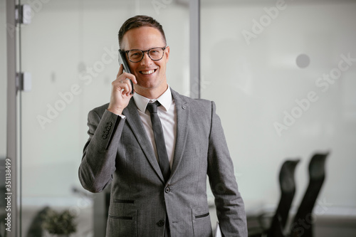 Businessman in office. Handsome man talking on phone at work. 