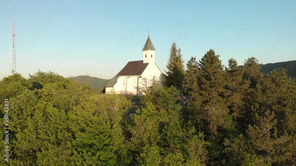 Drone fly close to old christian chapel stone sanctuary on the top of the hill reveal a stunning mountain landscape during a peaceful sunset Drone fly close to old christian chapel stone sanctuary on the top of the hill reveal a stunning mountain landscape during a peaceful sunset