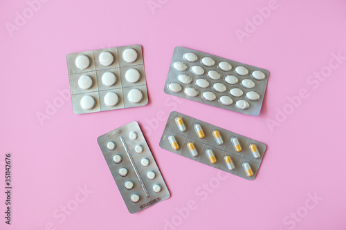 Pilll packaging on pink background. White tablets. 