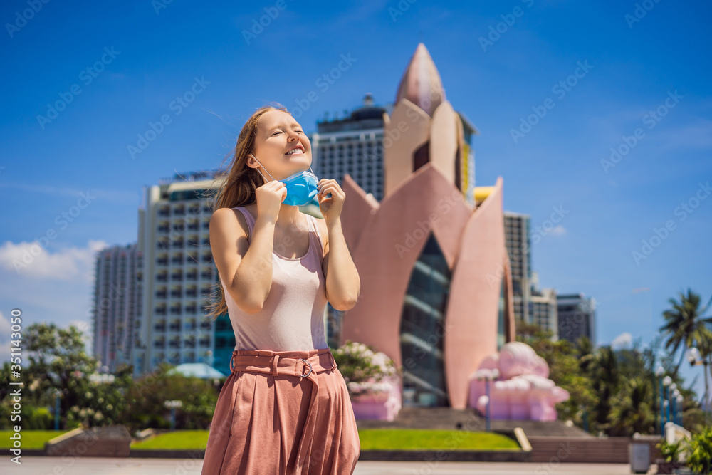 Fototapeta premium Woman tourist in Vietnam, Nha Trang put on a medical mask to protect herself from coronovirus infection COVID 19