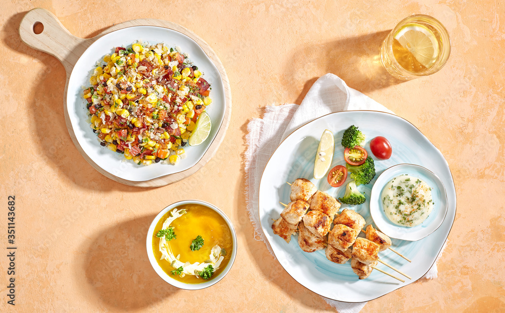 Combo menu set : Mexican salad, pumpkin soup and grilled chicken skewers. Flatlay angle