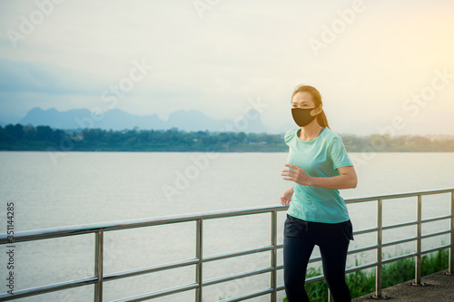 Asian woman running and exercise with wearing a protective mask COVID-19. © ParinPIX