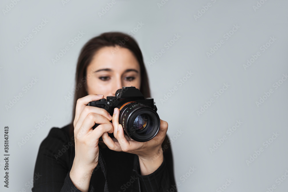 Young woman photographer takes photographs with modern digital camera in a photostudio. .Girl with a camera on a background of a white wall. Professional freelance work. Young woman photographer takes photographs with modern digital camera in a photostudio. .Girl with a camera on a background of a white wall. Professional freelance work.
