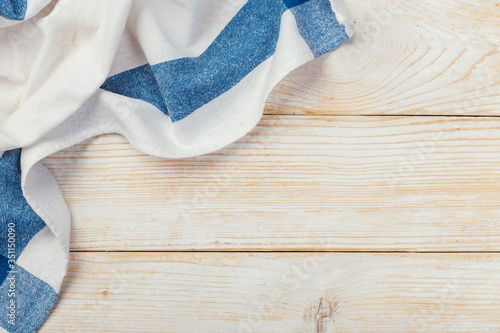 Top view on a white wooden table with a linen kitchen towel or textile napkin. a tablecloth on a light wood countertop.