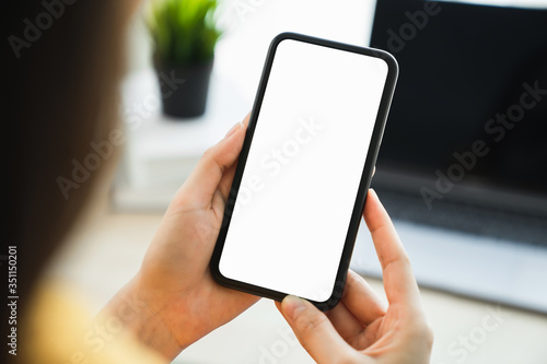 Woman hand holding smartphone and touching blank screen. Mockup of advertisement.