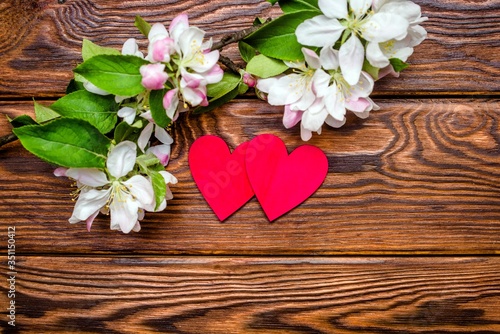 A symbol of love and a blooming Apple branch on a brown wooden background.