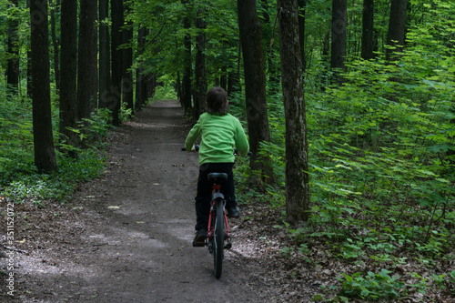 boy is riding a bike in deep dark green forest ,outdoor activities on fresh air, beautiful wild nature, healthy lifestyle