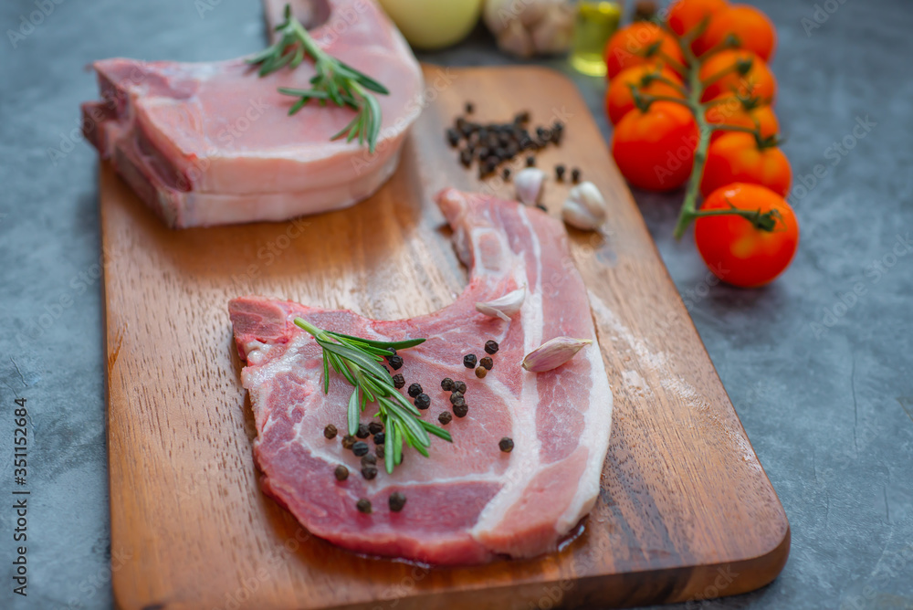 Fresh raw pork chops steak with pepper and rosemary on wooden background, home cooking, Quarantine COVID-19, soft focus, copy space.