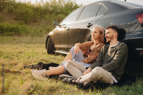 Beautiful young couple having fun at sunset near car