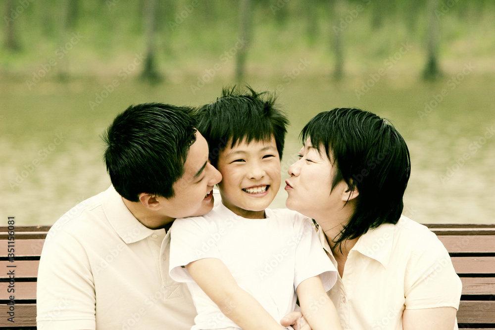 Boy getting kisses from his parents