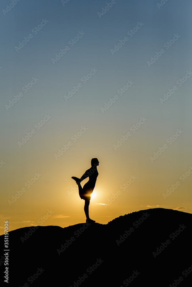 Silhouette of a girl doing yoga on a sunset background