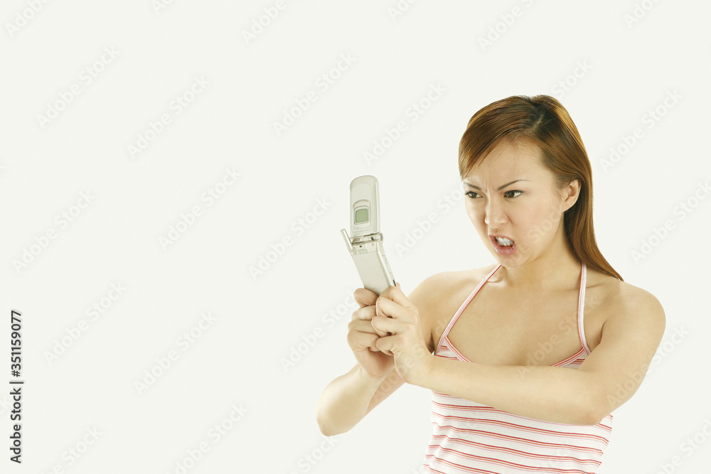 Woman staring angrily at her mobile phone Woman staring angrily at her mobile phone