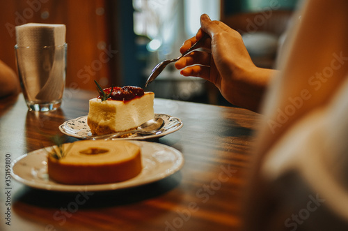 Young woman eating cheesecake strawberry, Close-up of female's hand using fork to get piece of cake.