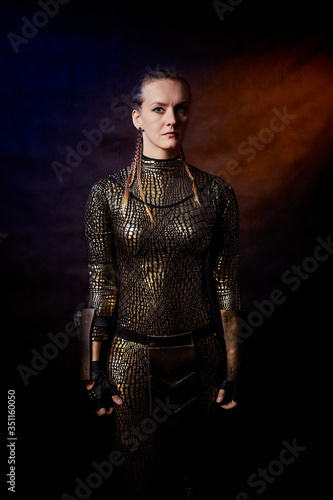 Valkyrie girl in shiny military armor in a dark room. Model during a photo shoot, the actress during the shooting of the film.
